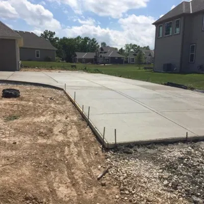 Affordable concrete contractors completing driveway project in a suburban neighborhood on a sunny day