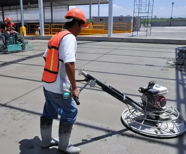 Commercial concrete flooring installation in Wauwatosa with workers smoothing the surface on a sunny day