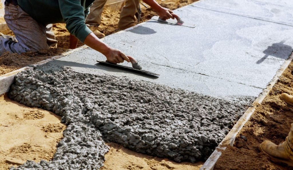 Workers removing a concrete slab using heavy equipment