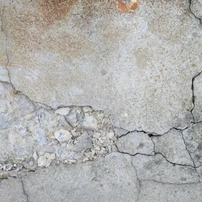 Textured concrete wall showing wear and cracks in an urban environment during daylight