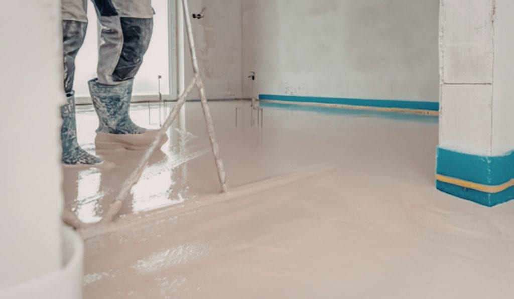 Worker applying epoxy coating on a concrete floor