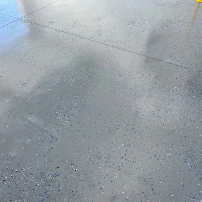 Shiny polished concrete floor reflecting a bright sky and clouds in an outdoor setting during the day