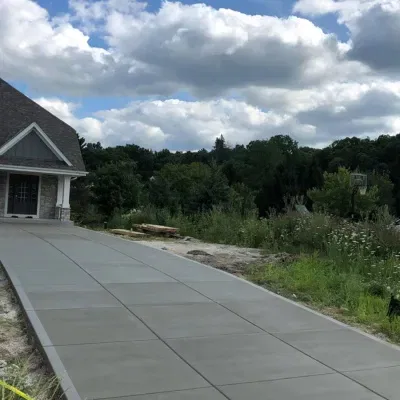 Residential driveway construction in West Allis Wisconsin with natural landscaping and cloudy sky above