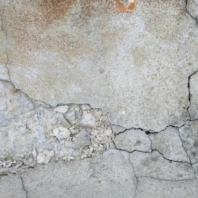 Textured concrete wall showing wear and cracks in an urban environment during daylight