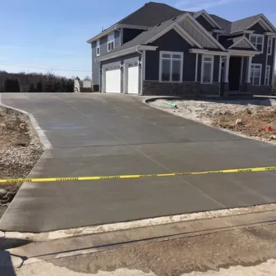 New driveway installation in Wauwatosa WI during a clear day with fresh concrete and construction barriers
