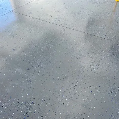 Shiny polished concrete floor reflecting a bright sky and clouds in an outdoor setting during the day